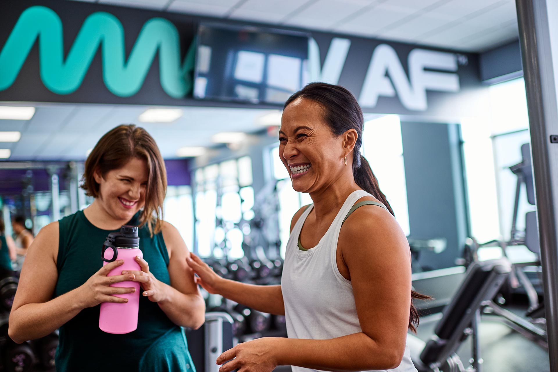 A man and woman walking into the entryway of an Anytime Fitness gym