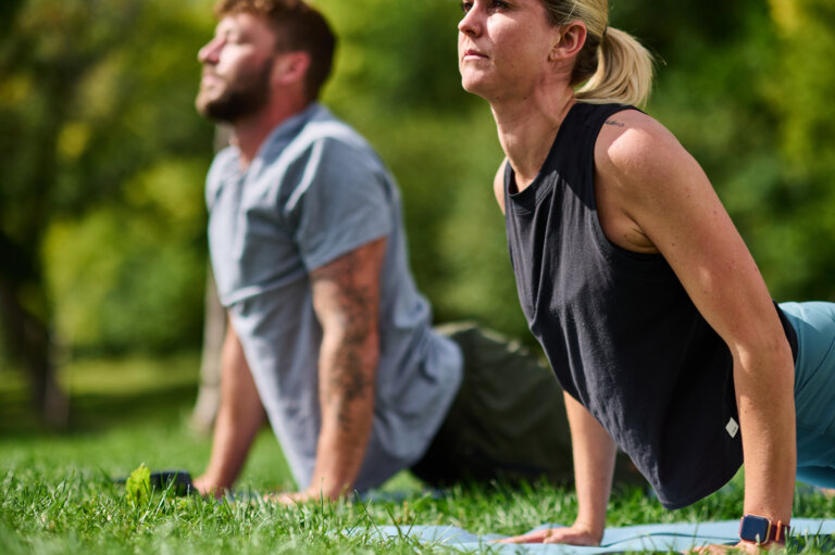 Couple performing a spinal stretch on a mat.