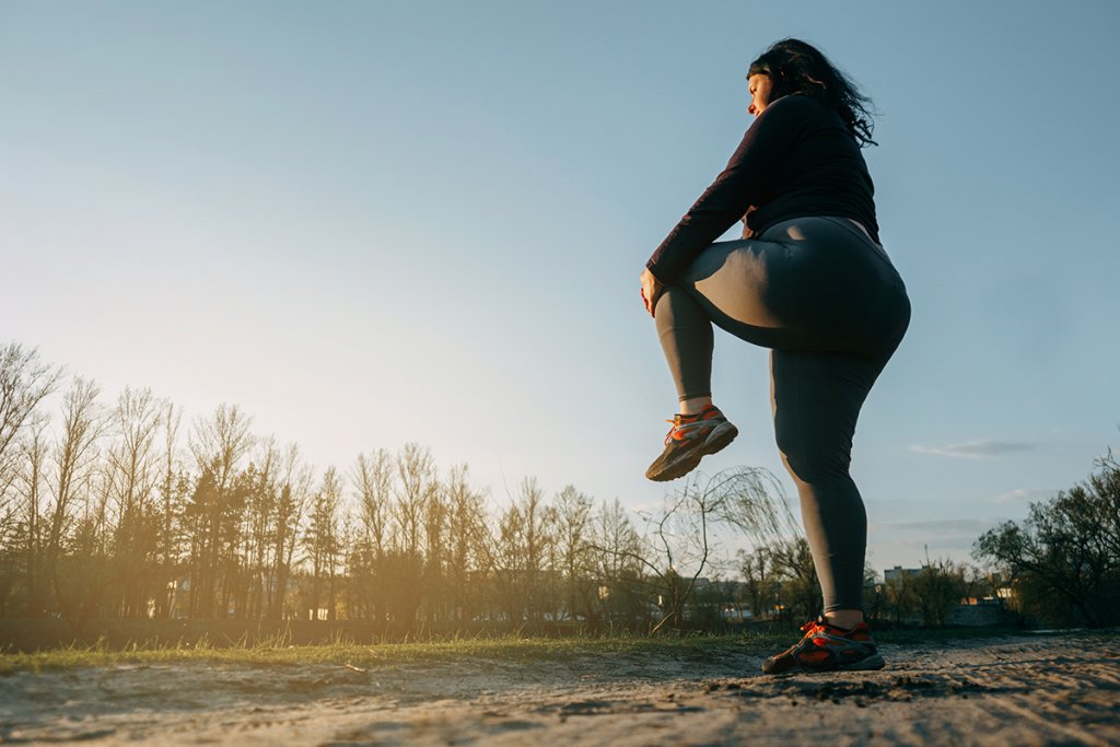 Woman warming up for an outdoor run on a dirt road.