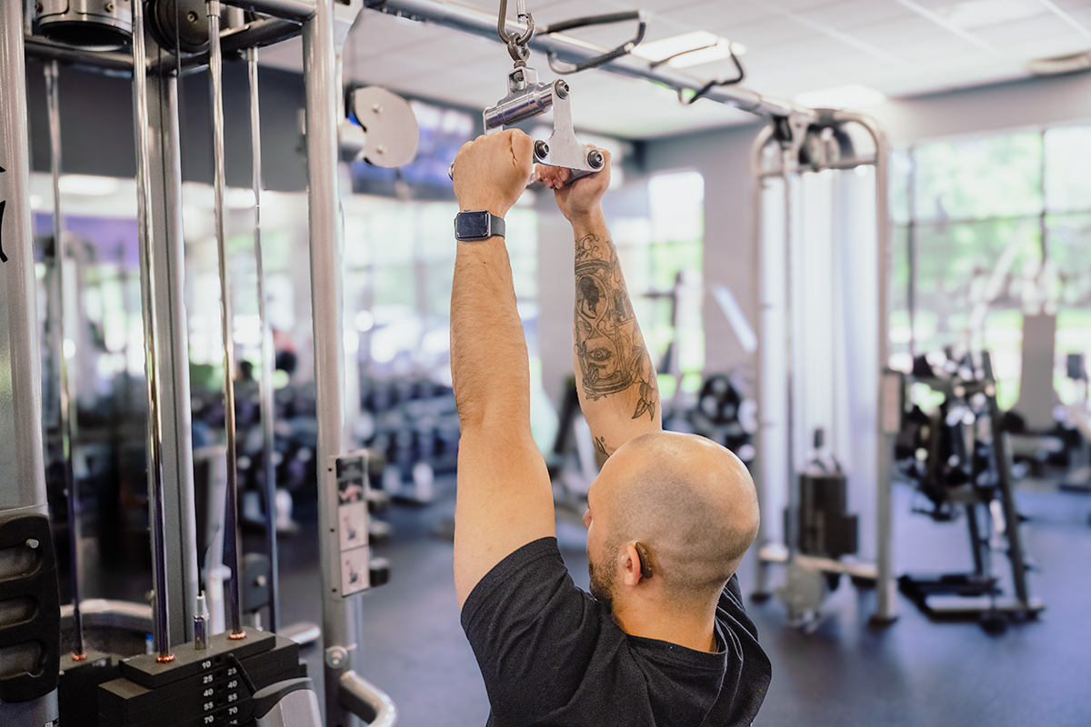 Close-up of Coach Mike demonstrating a neutral grip on the lat pulldown bar in a gym.