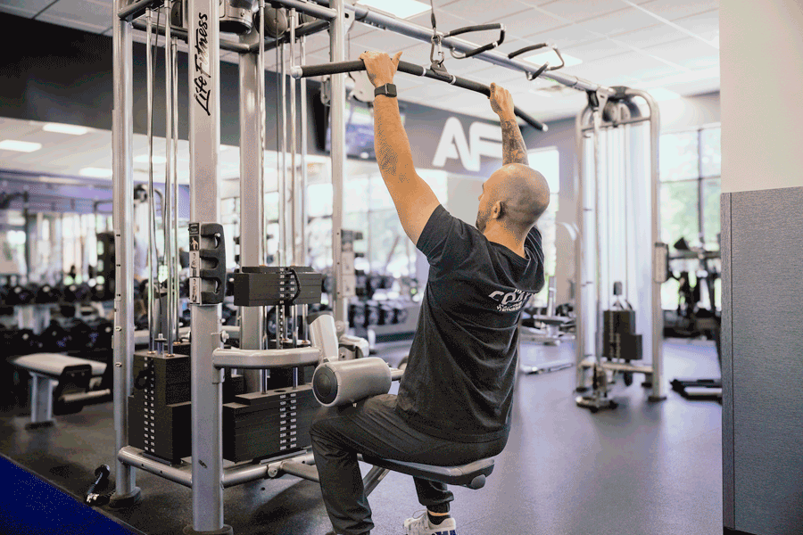 Coach Mike demonstating how to do a lat pulldown on a cable machine.