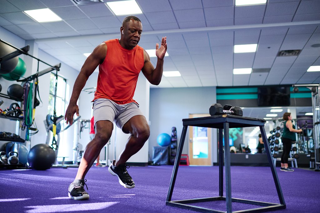 Man in a red shirt doing a HIIT workout plan at the gym.