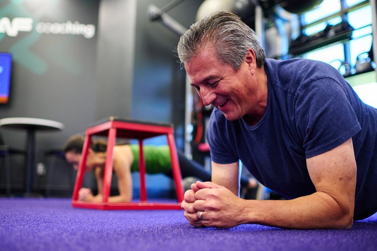 Man holding a plank during a group workout in a gym setting.
