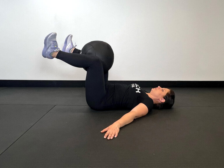Coach lays on back with knees up, holding the medicine ball between the legs.