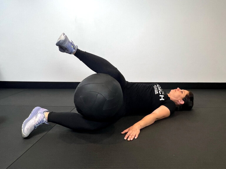 Coach lays on back while holding medicine ball between the knees and twists torso to the left.