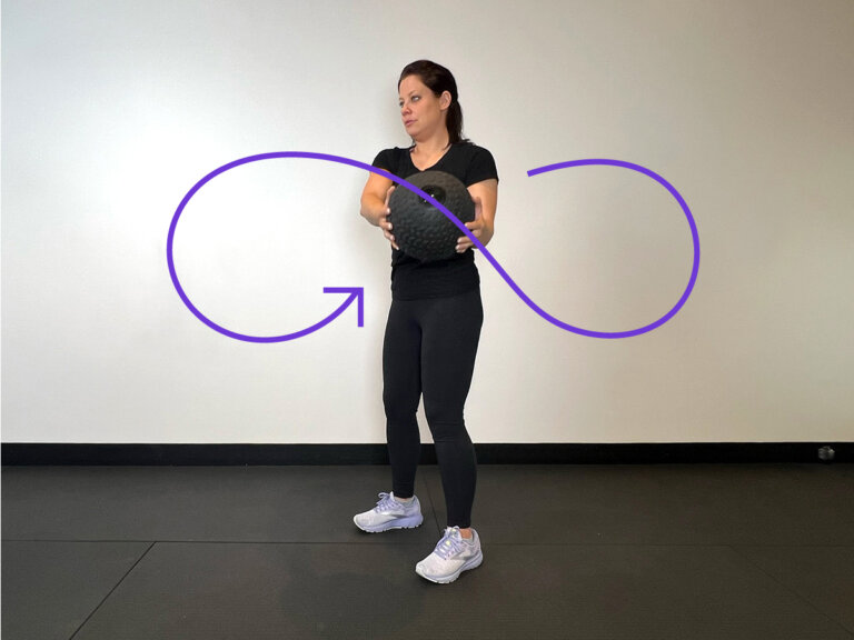 Coach holds medicine ball up over right shoulder.