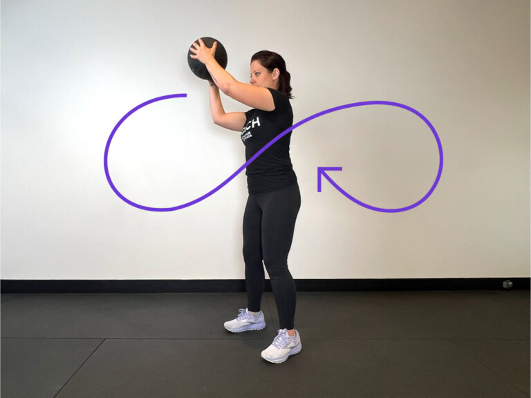 Coach holds medicine ball to the left of the body.