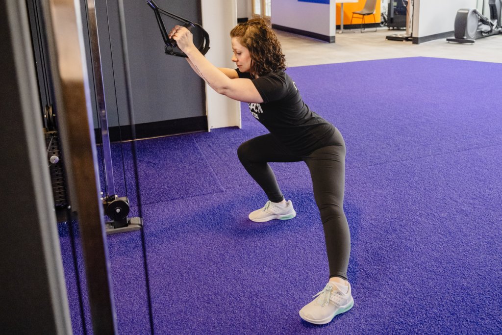 Coach Heather demonstrating an assisted lateral lunge with TRX straps.