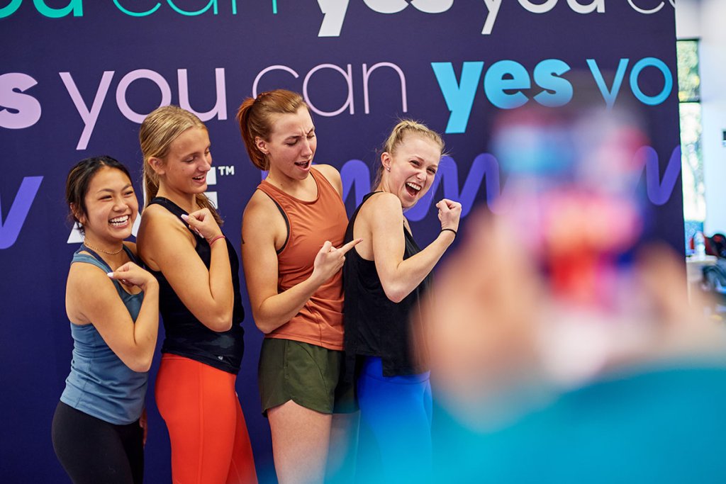 Four young women taking a group photo in the gym.