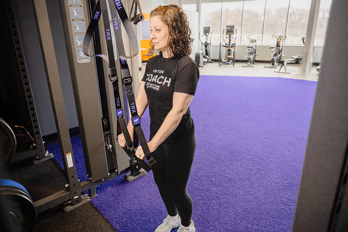 Coach Heather demonstrating an assisted hip hinge with TRX straps.