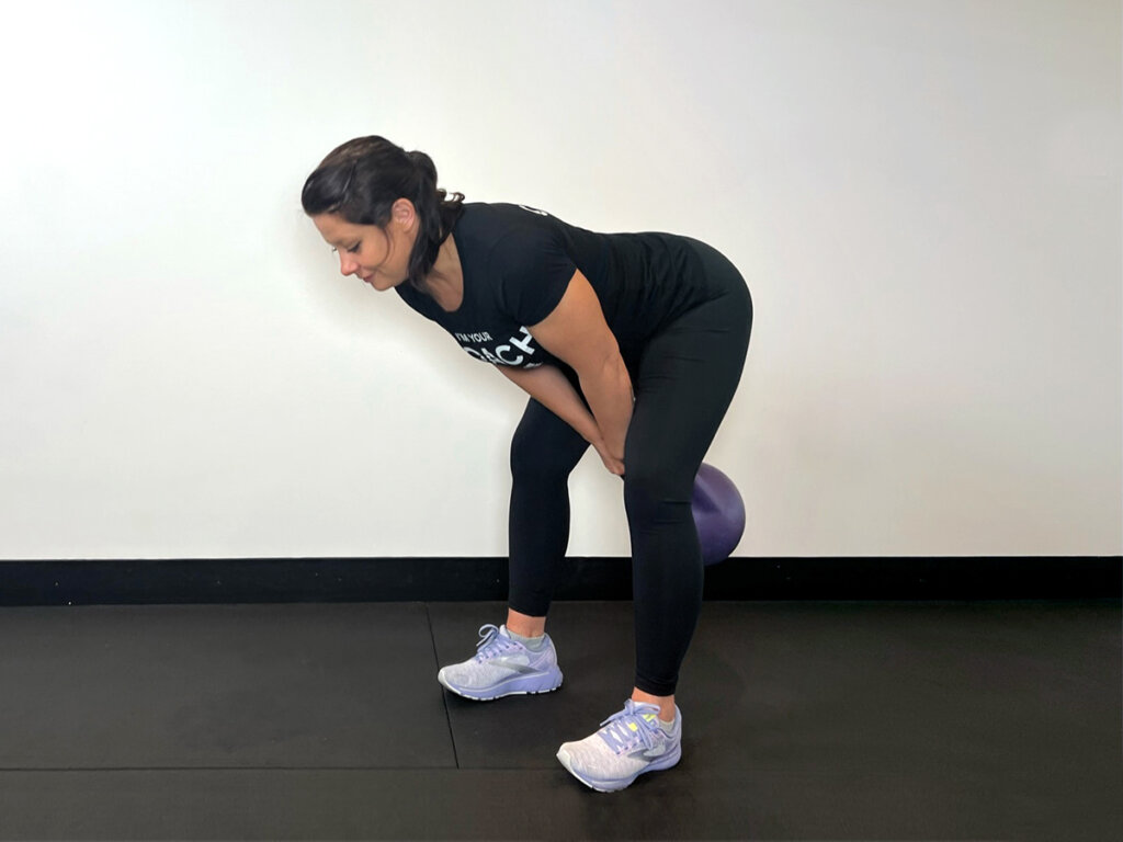 Coach swinging kettlebell between her legs, back straight.