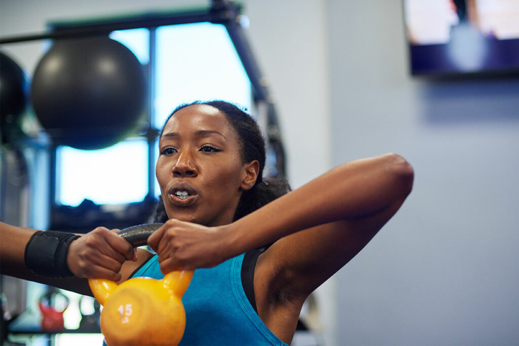 Woman doing a kettlebell deadlift exercise in a gym. 