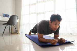 Man doing a plank in his living room on a mat.