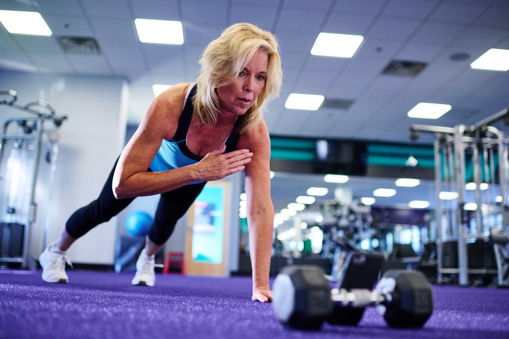 Woman doing a crossbody plank at Anytime Fitness.