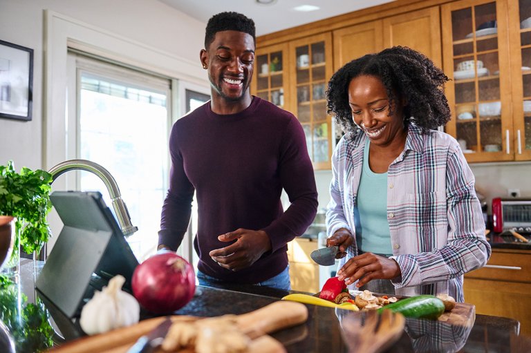 Man and woman chopping vegetables in a kitchen.