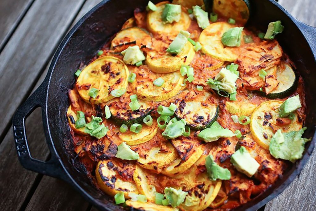 20-minute healthy zucchini enchilada skillet topped with cheese, avocado, and green onion.