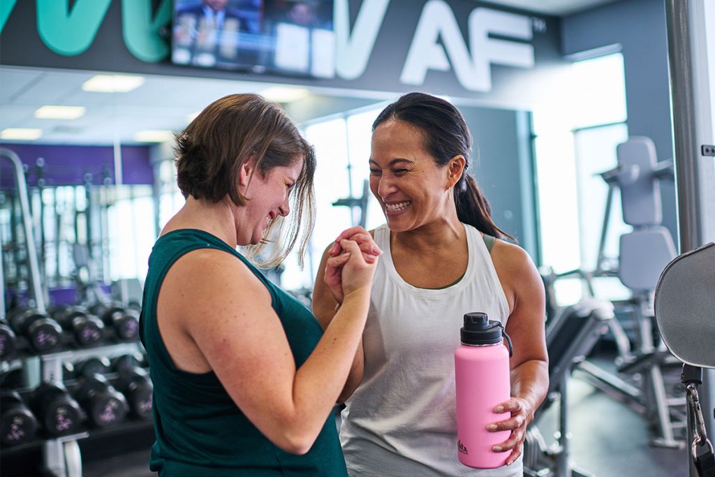 Two women bonding in a gym post-workout.
