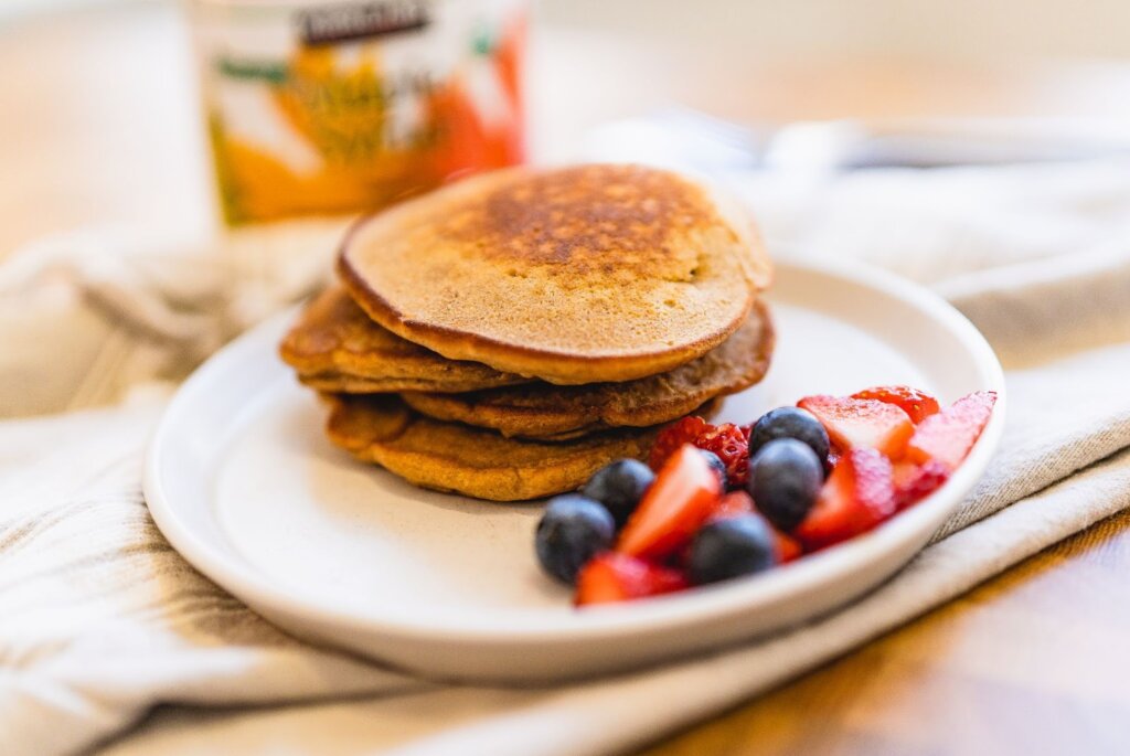 Stack of four pancakes with strawberries and blueberries.