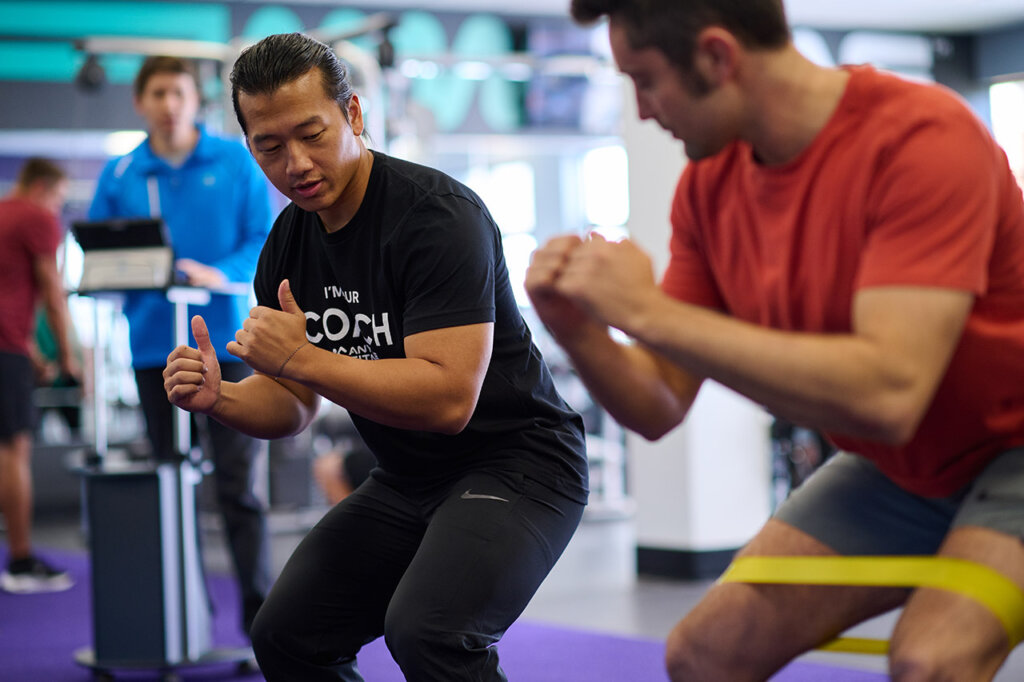 Coach demonstrating band exercise form to member