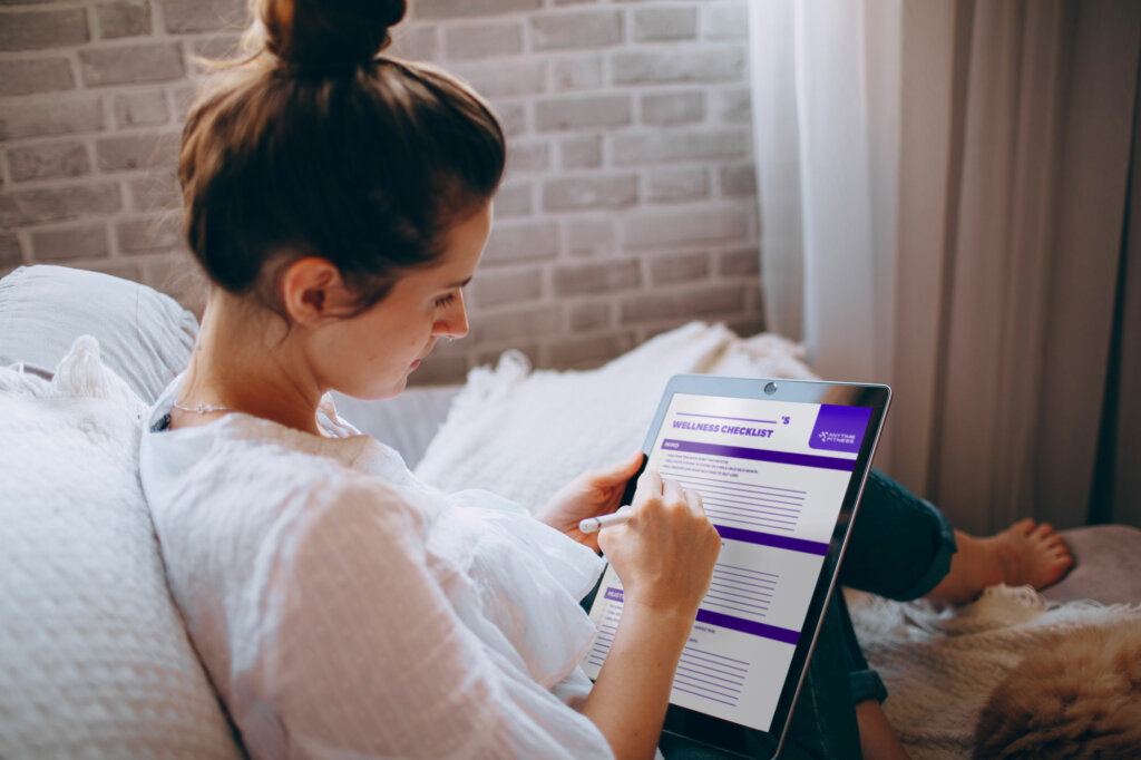 Woman sitting on couch, filling out her wellness checklist.