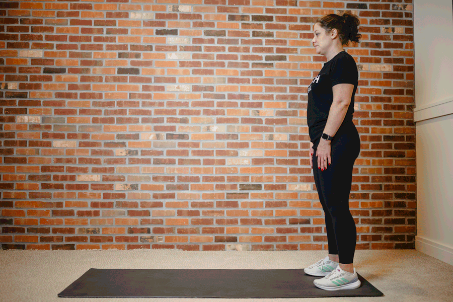 Anytime Fitness Coach performing inchworms on an exercise mat in a home gym, strengthening the core.