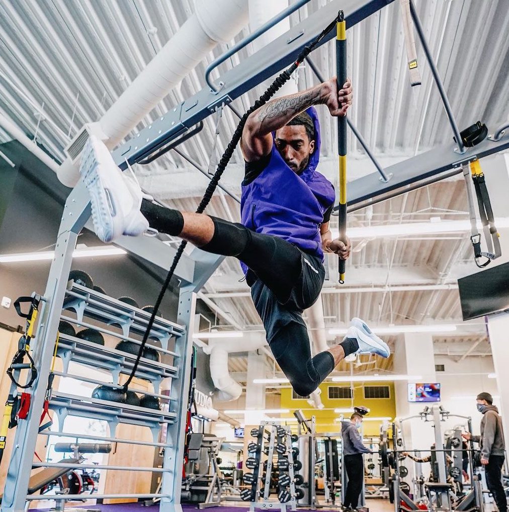 Coach doing an exercise in a gym with an athletic jump and a core-training tool in use.