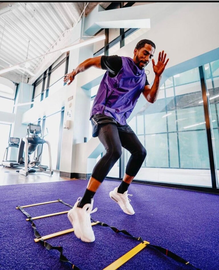 Coach exercising in a gym using an agility ladder.