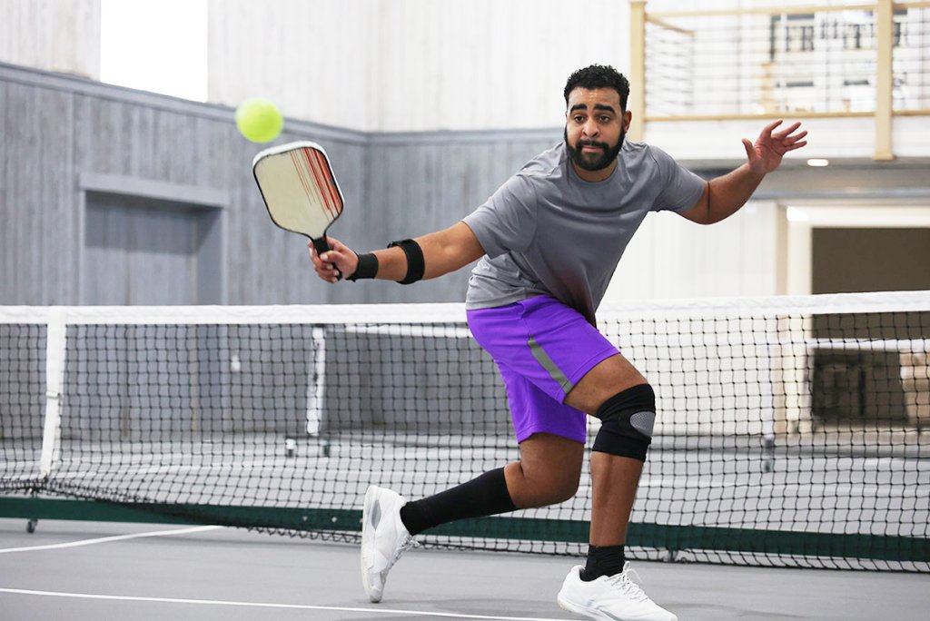 Man playing pickleball in an indoor court.