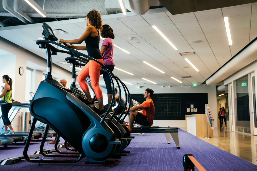 Two women using stair climber machines in a gym.