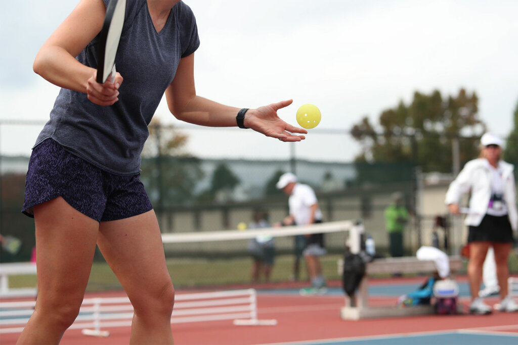 Woman playing pickleball on an outdoor court.