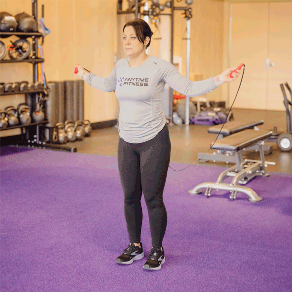 Coach jumping rope, swinging the rope around her body twice before she hits the ground.