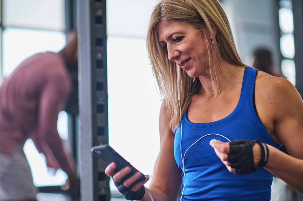 A woman using her phone in a gym.
