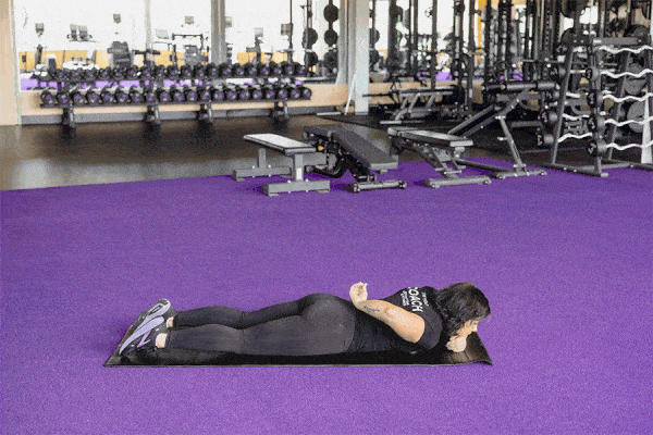 Coach performing a swimmer movement on a gym mat.