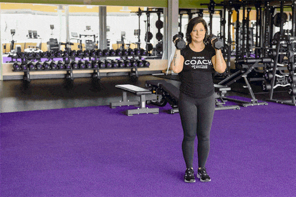 Coach Heather demonstrating a Lateral Lunge with weights in a gym setting.