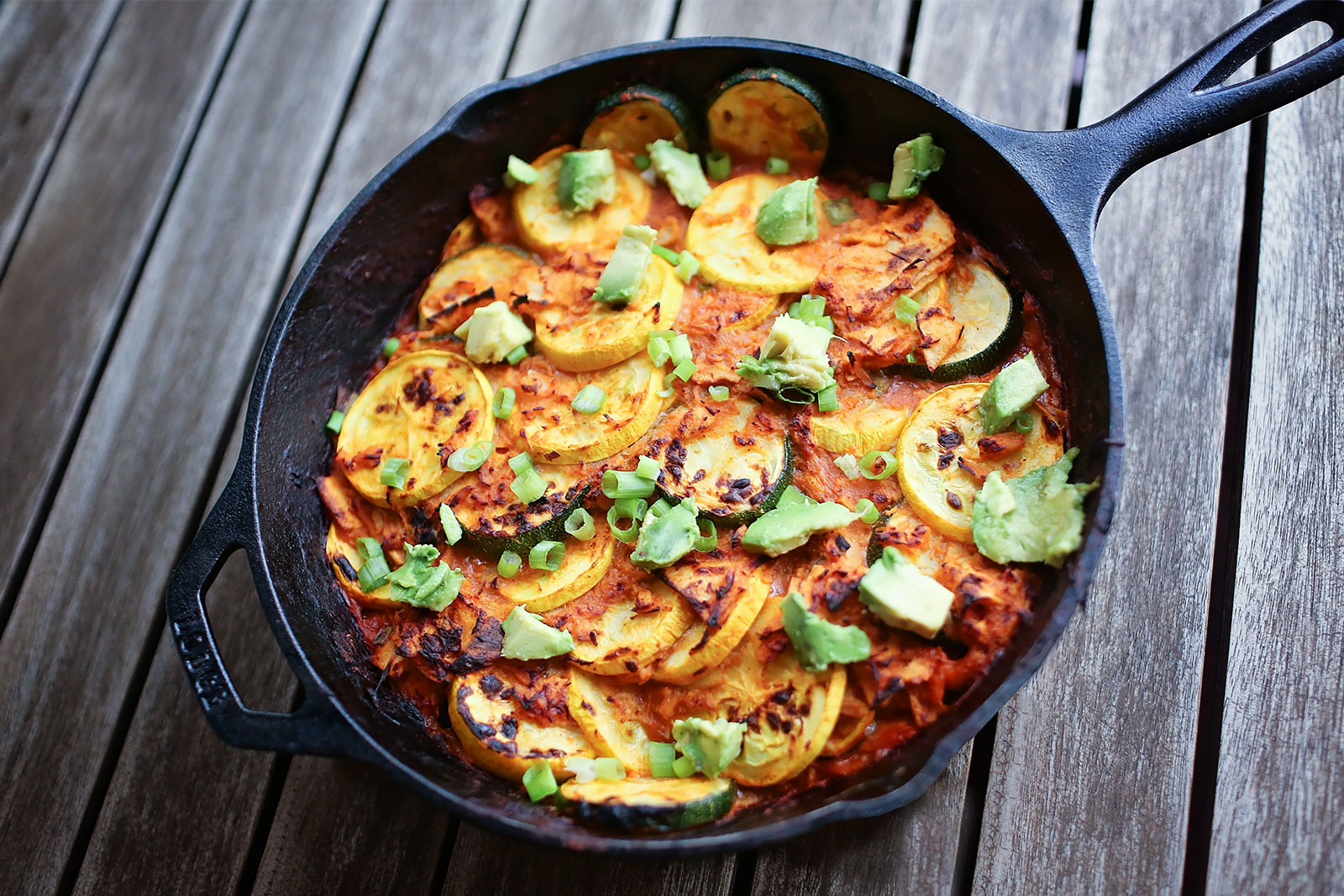 20-minute healthy zucchini enchilada skillet topped with cheese, avocado, and green onion.