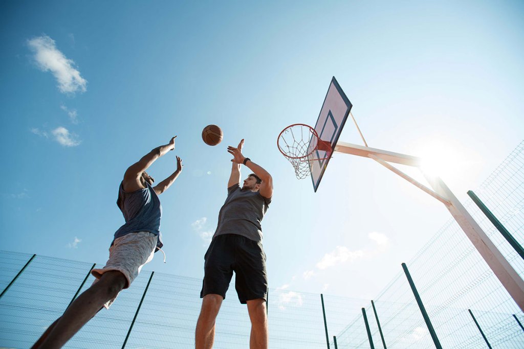 Two people playing basketball on an outdoor court.