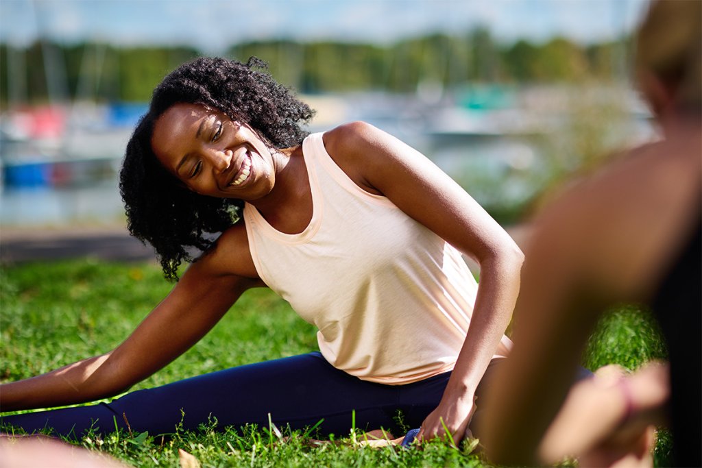 Woman stretching in the grass during an outdoor workout.