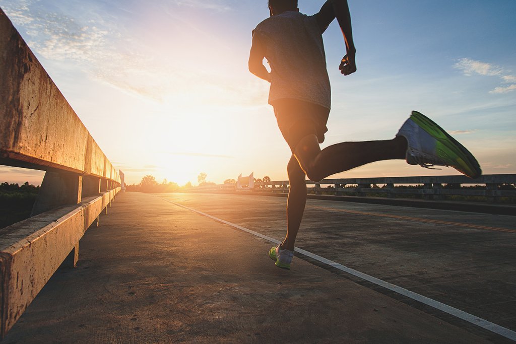 Person running on a road while the sun is setting.