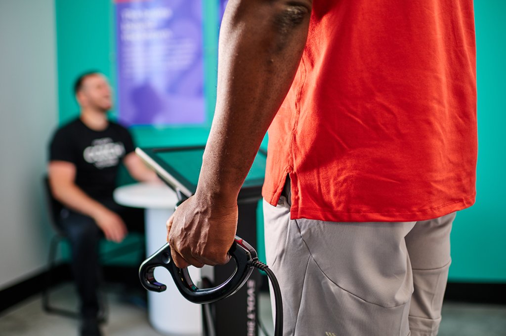 Man holding the handle of an Evolt body scanner during a fitness consultation.