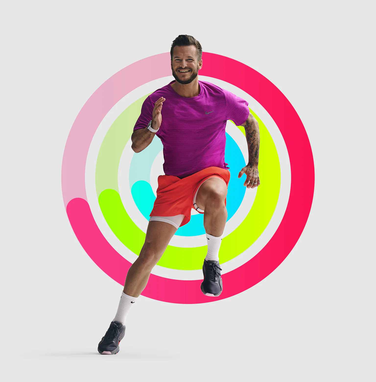 Man in a running position with partially closed Apple Fitness rings behind him