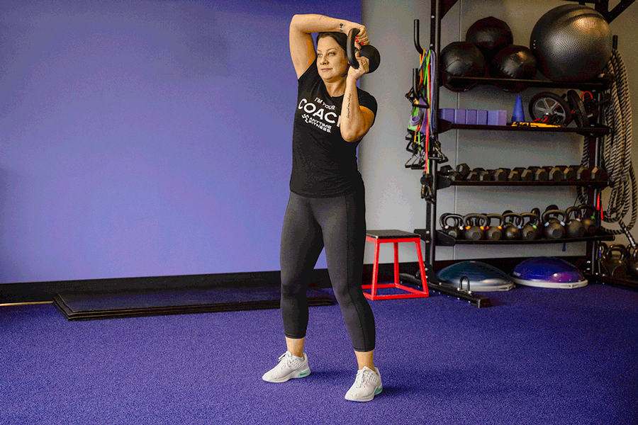 Coach Heather demonstrating a halo with a kettlebell.