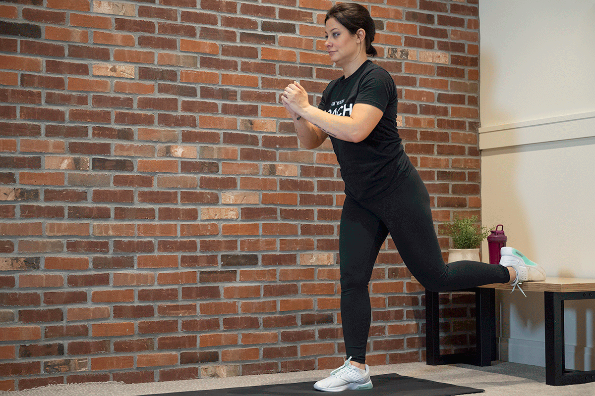 Woman squatting with her left foot up on a bench behind her.