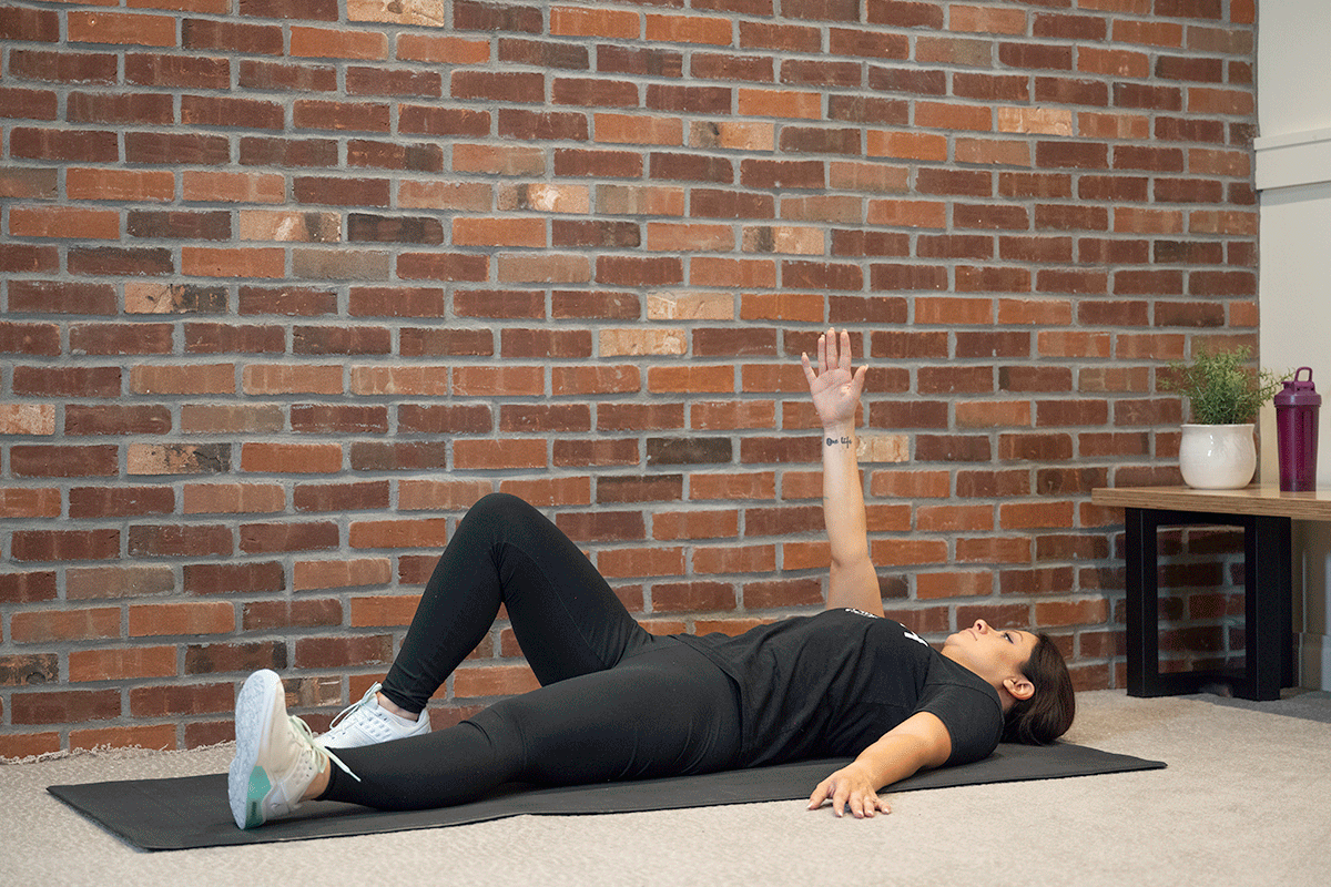 Woman performing a quarter get-up on a yoga mat in her living room.