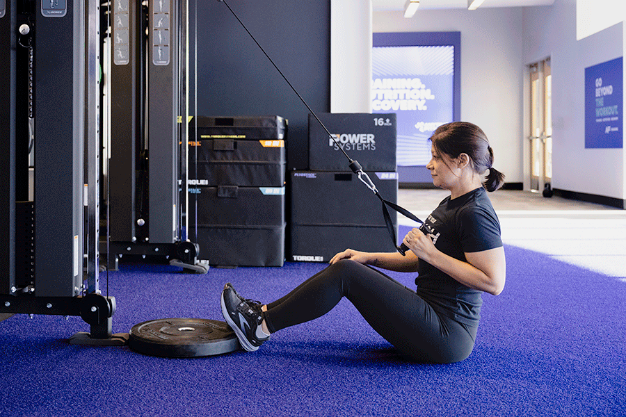Woman doing reps of single-arm pulldown exercises in a gym setting as part of her pull workout.