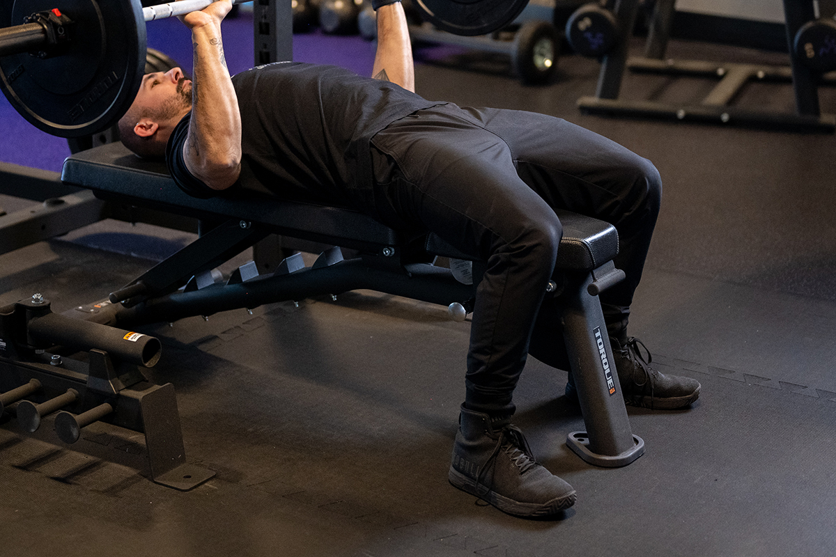 Anytime Fitness Coach Mike demonstrating how to flatten the back while bench pressing.