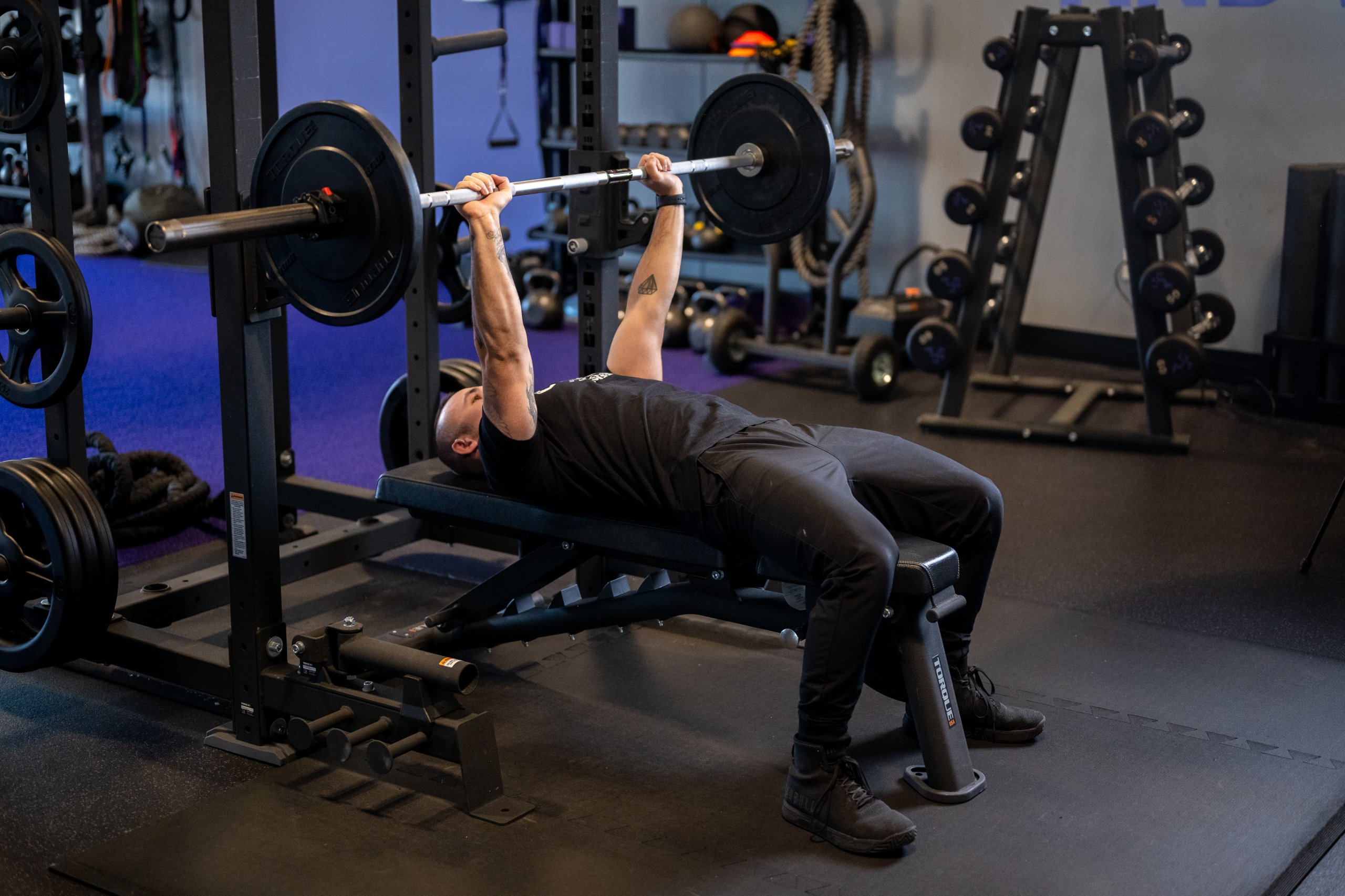 Anytime Fitness Coach Mike demonstrating how to bench press with proper form while raising the bar.