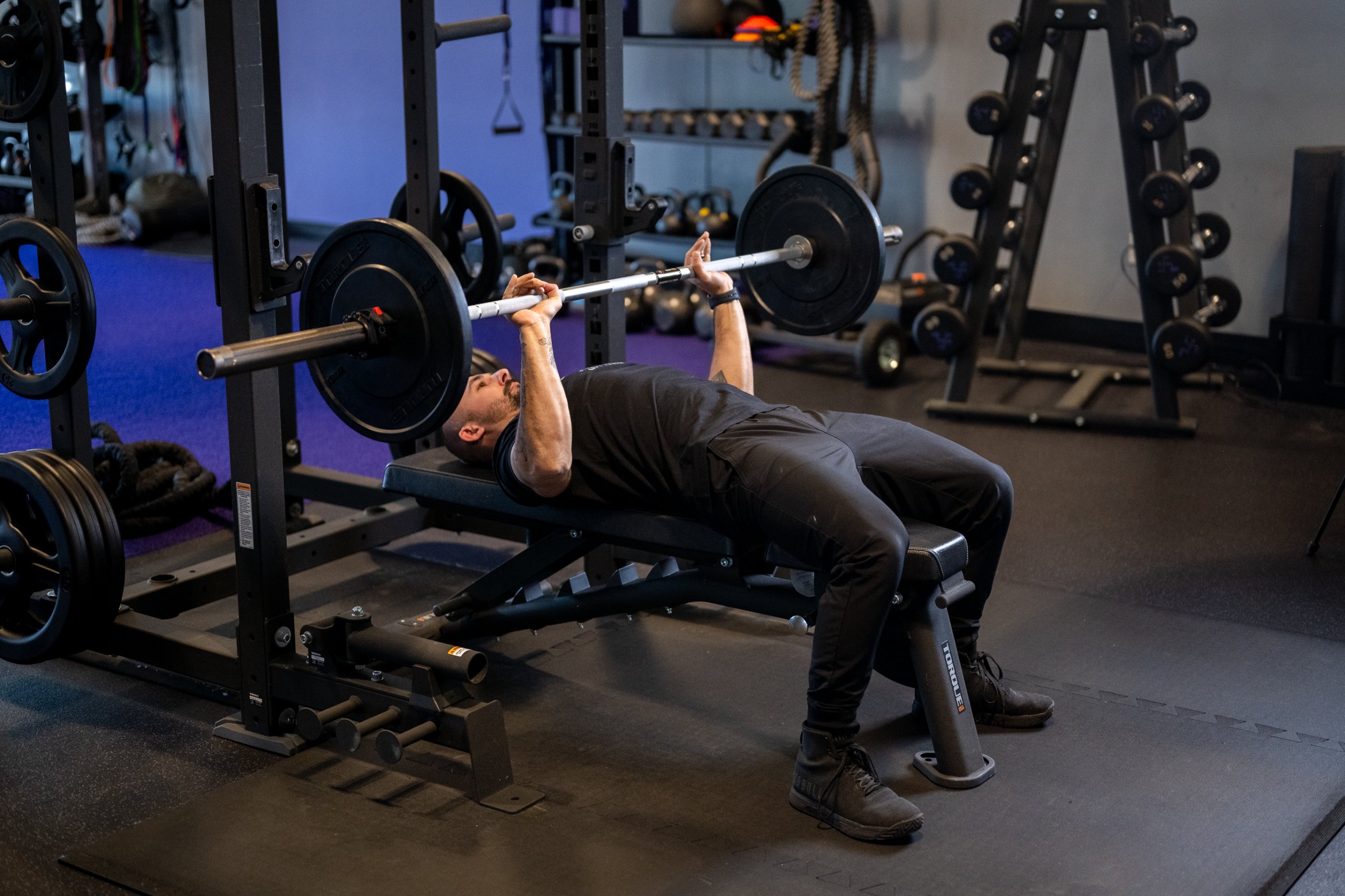 Anytime Fitness Coach Mike demonstrating how to bench press with proper form with the barbell above his chest.