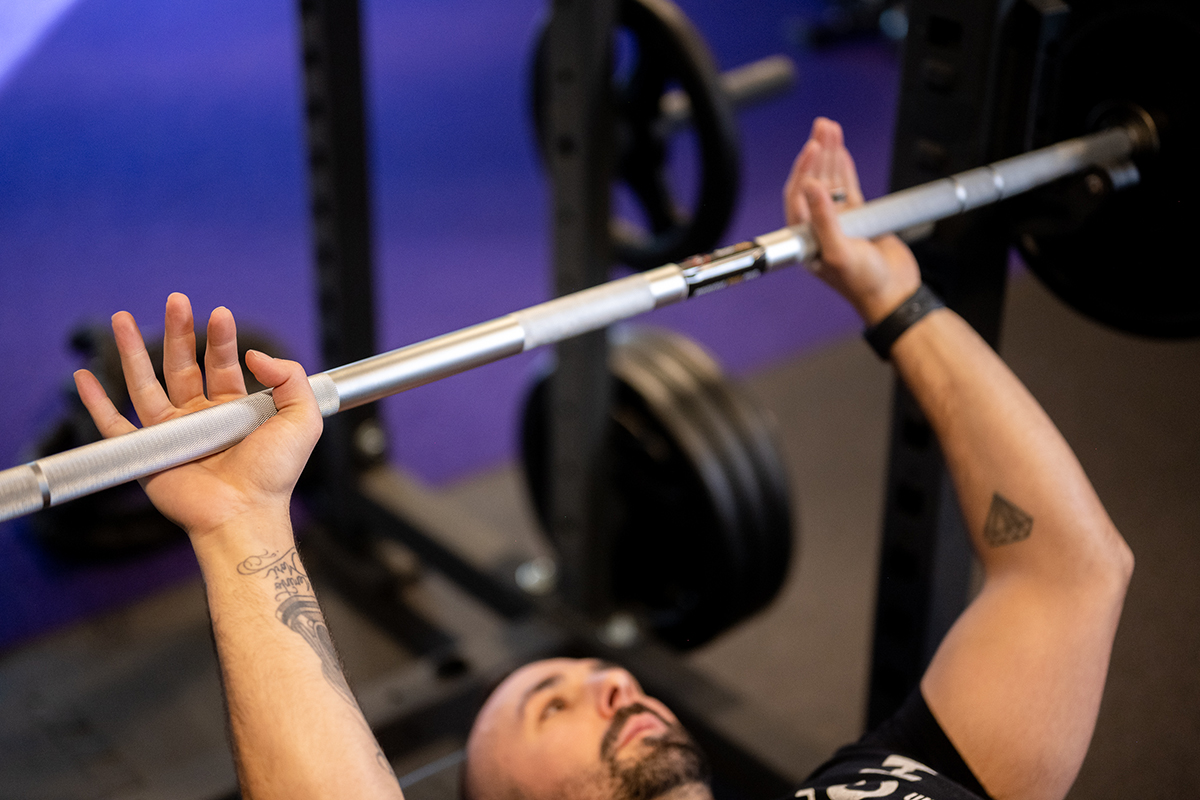 Anytime Fitness Coach Mike demonstrating how to bench press with the correct hand position on the barbell.