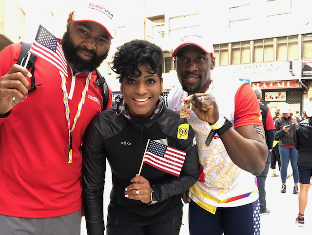 Mark with his Coaches, Sam and Devon, holding USA flags and dressed to represent the United States at the Duathlon World Championships in Spain.