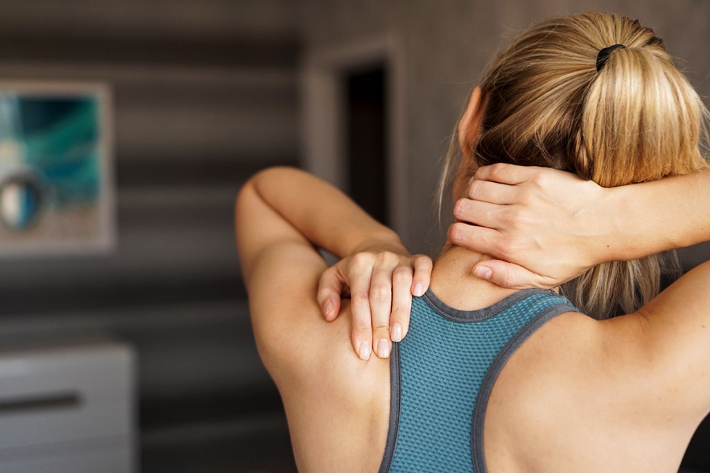 Woman stretching her neck and rubbing her shoulder blade.